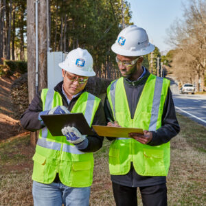 Two people in hard hats looking at tablet