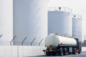 road tanker in front of oil refinery tanks