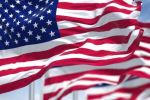 Three flags of the United States of America waving in the wind. Clear sky in the background. Selective focus. Democracy, independence and election day. Patriotic symbol of American pride